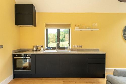 cocina con fregadero y ventana en Meadow Barn, en Axminster