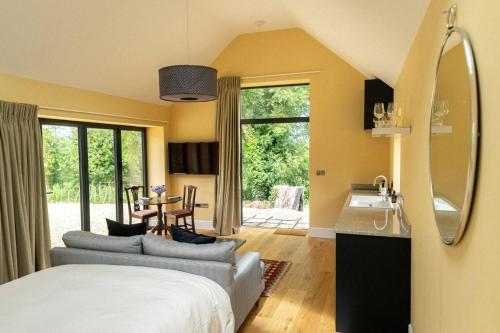 a bedroom with a bed and a kitchen with a sink at Meadow Barn in Axminster