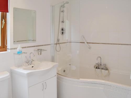 a white bathroom with a sink and a bath tub at Fairways Lodge in Bridlington