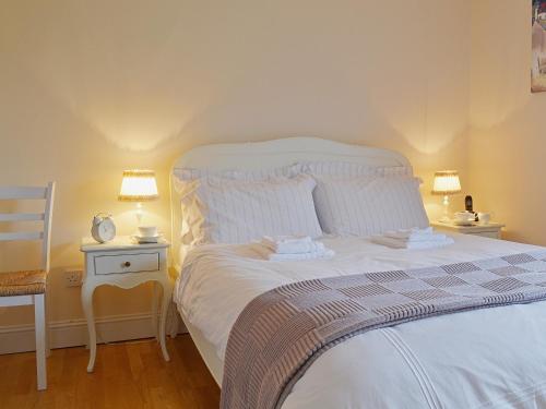 1 dormitorio con 1 cama blanca grande y 2 lámparas en Mill Cottage, en Comrie