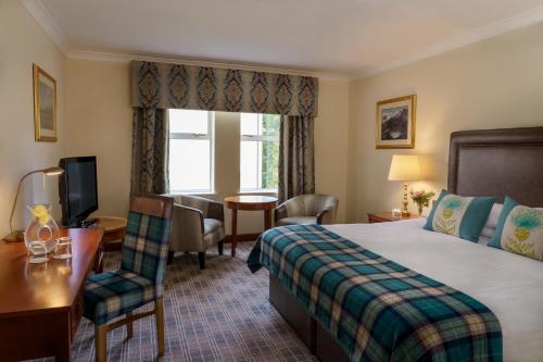 イースト・キルブライドにあるMacdonald Crutherland Houseのベッド、デスク、窓が備わるホテルルームです。