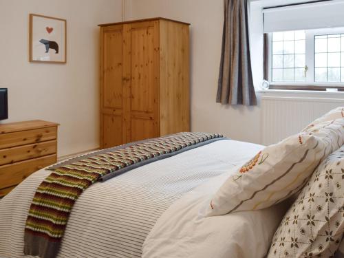 a bedroom with a bed with a dresser and a window at Hill View Cottage in Snowshill