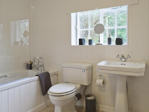 a white bathroom with a toilet and a sink at Hill View Cottage in Snowshill