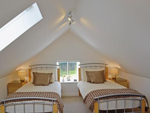 two beds in a attic room with a window at Song Bird Cottage in Lochend