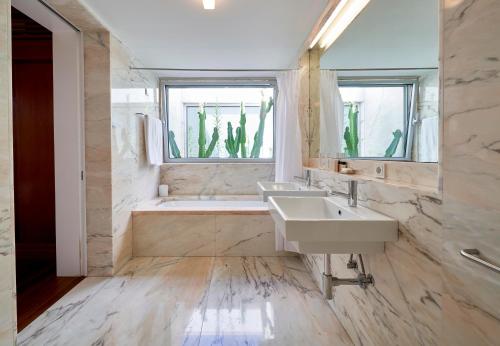 a bathroom with two sinks and a tub and a window at Hotel Porto Santo & Spa in Porto Santo