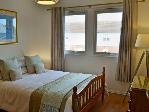 a bedroom with a large bed with two windows at Sandy View in Beadnell
