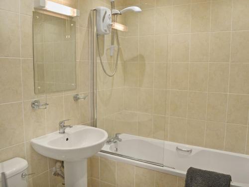 a bathroom with a sink and a shower and a tub at Sandy View in Beadnell