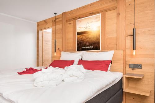 een slaapkamer met een groot wit bed met rode kussens bij Chalet-Ferienwohnung Kornspeicher, 70 qm, Wellness/Fitness/Sauna – Bergrödelhof in Feilitzsch