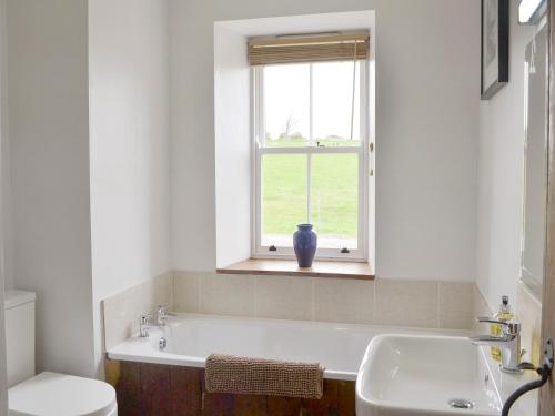 a bathroom with a sink and a toilet and a window at The Coach House in Whittingham