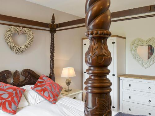 a bedroom with a bed with a wooden post at The Coach House in Whittingham