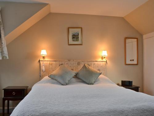 een slaapkamer met een groot wit bed met 2 kussens bij Edenwoodend Cottage in Kilmaron