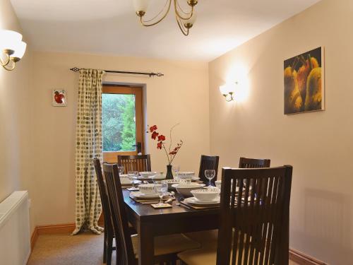 comedor con mesa negra y sillas en Shippon Cottage - E4299a, en Halston