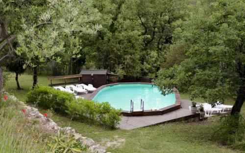 une piscine avec des chaises blanches et une terrasse en bois dans l'établissement Le mas du goio, à Seillans