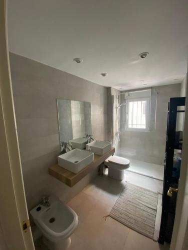 une salle de bain avec deux lavabos et un WC et un miroir dans l'établissement Príncipe habitaciones, à Madrid