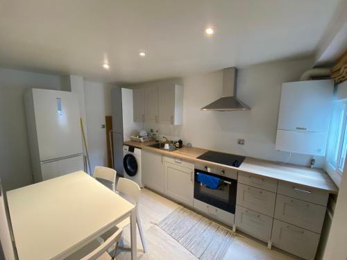 une cuisine avec des armoires blanches, une table et une cuisinière dans l'établissement Príncipe habitaciones, à Madrid