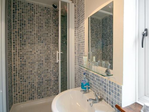 ein Bad mit einem Waschbecken und einer Dusche mit einem Spiegel in der Unterkunft Lindas Lodge in Holton