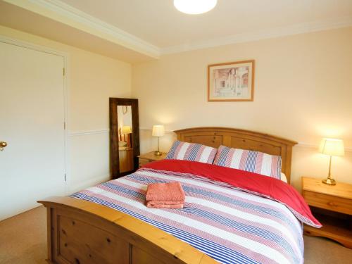 a bedroom with a wooden bed with two towels on it at Lindas Lodge in Holton