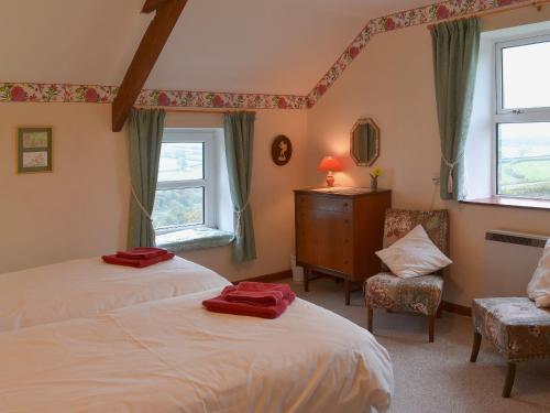 a bedroom with two beds and a chair and windows at The Stables in Dunterton