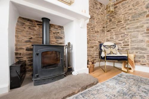 uma lareira de pedra numa sala de estar com uma cadeira em Luxury Cottage near Hay-on-Wye em Llanigon