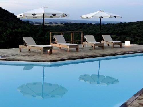 una piscina con sillas y sombrillas. en Villa Serrana - Mesón de las cañas, en Villa Serrana