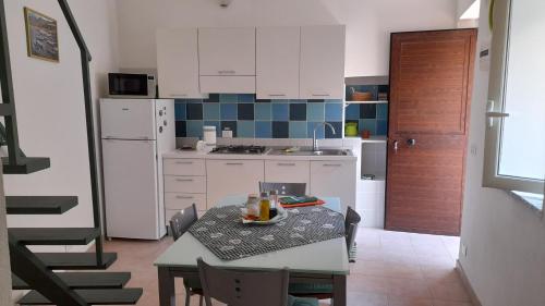 a kitchen with a table and a kitchen with white cabinets at Zephyros - VIVERE IL MARE E LA STORIA DEL BORGO in Santa Caterina dello Ionio
