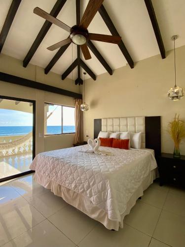 a bedroom with a large bed with a ceiling fan at Vista Las Olas Resort in El Cuco