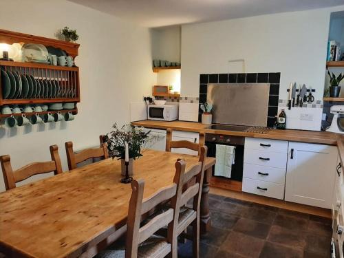 a kitchen with a wooden table with chairs and a kitchen with a refrigerator at Selah Teifi spectacular river view with games room in Llandysul
