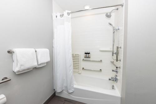 a bathroom with a shower and a tub and a toilet at Avid Hotels - Denver Airport Area by IHG in Denver