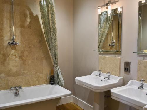 a bathroom with two sinks and a mirror at Mill Cottage in Ravensworth