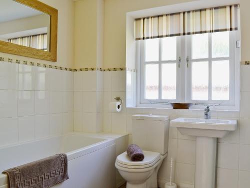 a bathroom with a tub and a toilet and a sink at Bowles Cottage in Lechlade