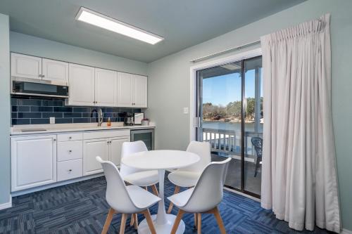 a kitchen with white cabinets and a table and chairs at The Hamilton - Lakefront & Studio Suites, Hot Springs in Hot Springs