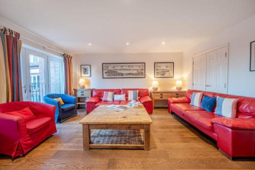 ein Wohnzimmer mit roten Sofas und einem Holztisch in der Unterkunft The Pilchard by Big Skies Cottages in Wells next the Sea