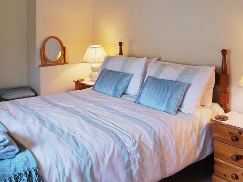 a bedroom with a large bed with two blue pillows at Pegg Inn Cottage in Allgreave