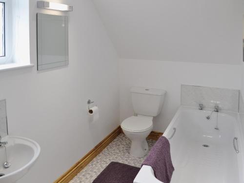 Baño blanco con aseo y lavamanos en The Old Coach House, en St Austell