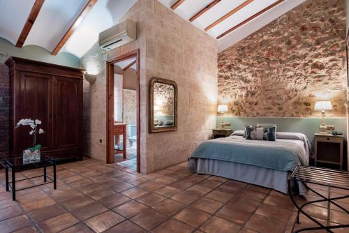 a bedroom with a bed in a room with a stone wall at Hotel Casa Babel in Villalonga