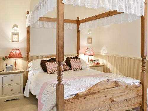 a bedroom with a wooden canopy bed with two lamps at Primrose Cottage - Lpg in Ireby