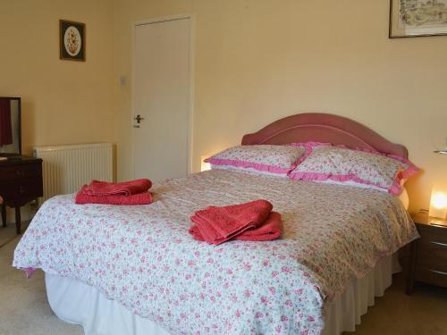 a bedroom with a bed with two red towels on it at Broadstone Cottage in Norham
