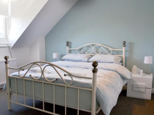 a bedroom with a white bed with a white frame at Dovecote House in Wooler