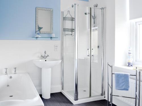 a white bathroom with a shower and a sink at Dovecote House in Wooler