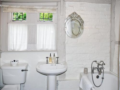 a white bathroom with a sink and a bath tub at Hathaway Hamlet in Stratford-upon-Avon