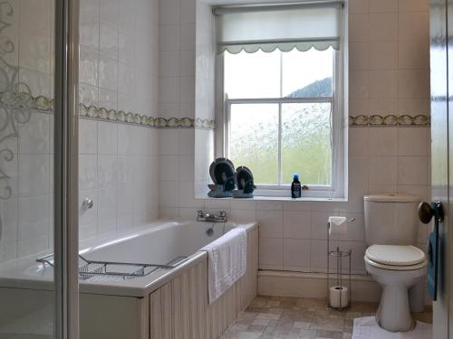 baño con bañera, aseo y ventana en Smithy House en Betws-y-coed