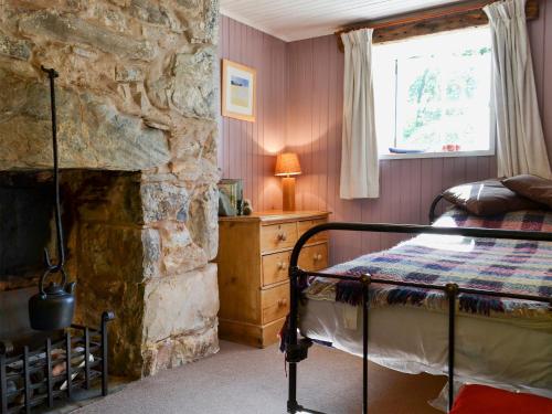 - une chambre avec un lit et une cheminée en pierre dans l'établissement Old Mill Cottage, à Acharra