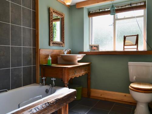 La salle de bains est pourvue d'une baignoire, d'un lavabo et de toilettes. dans l'établissement Old Mill Cottage, à Acharra