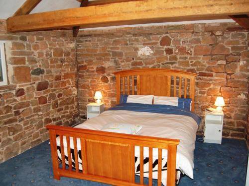 1 dormitorio con cama de madera en una pared de ladrillo en The Bird Bath, en Wreay