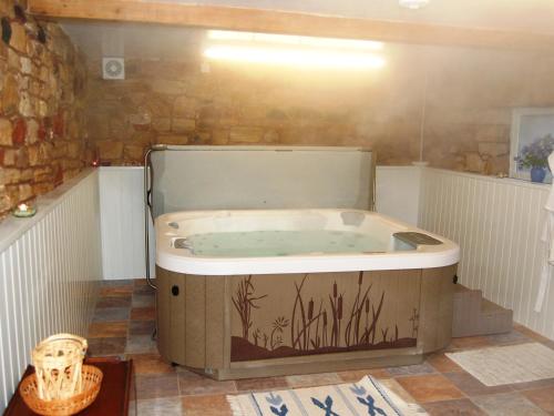 una bañera de hidromasaje en una habitación con una pared de ladrillo en The Bird Bath, en Wreay