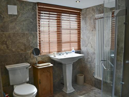 a bathroom with a sink and a toilet and a shower at West End Cottage in Whittingham