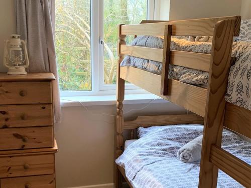 a bedroom with a bunk bed and a window at Sandpipers in Pyworthy