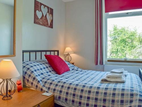 a bedroom with a bed with a red pillow and a window at Parkview in Skipton