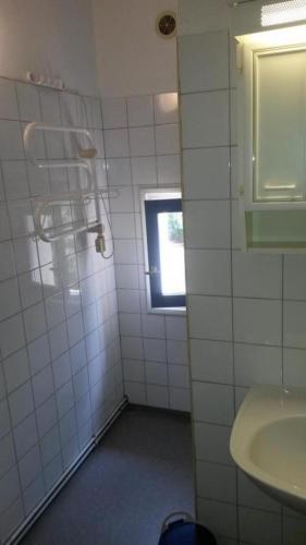 La salle de bains est pourvue de carrelage blanc, d'un lavabo et d'une fenêtre. dans l'établissement Les restanques de provence, à Bandol