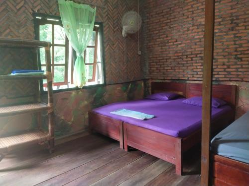 a bedroom with a purple bed in a brick wall at Mountain View Cottages & Villa Tangkahan in Tangkahan